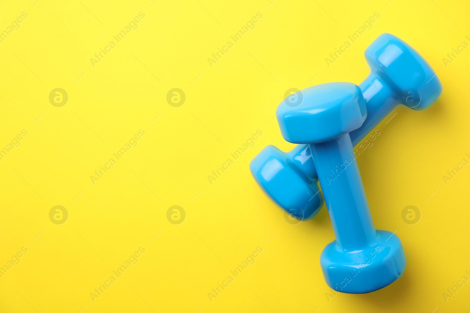 Photo of Bright dumbbells and space for text on color background, flat lay. Home fitness