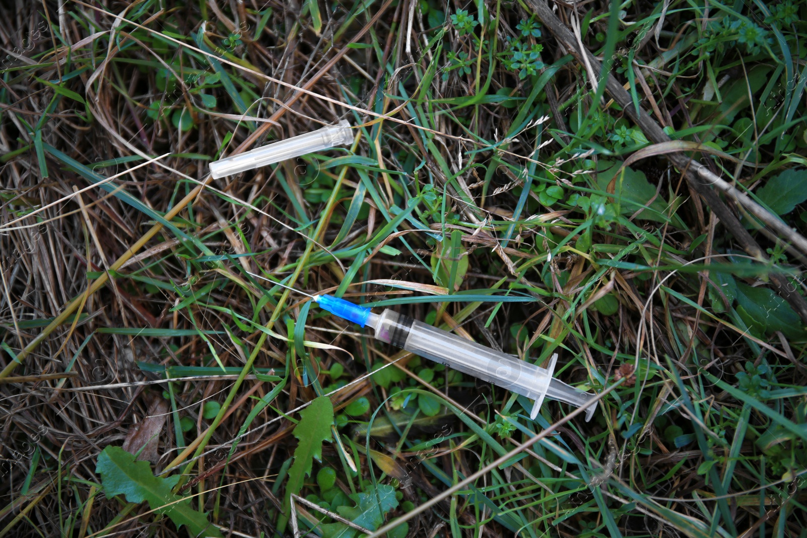 Photo of Empty syringe on green grass outdoors, flat lay