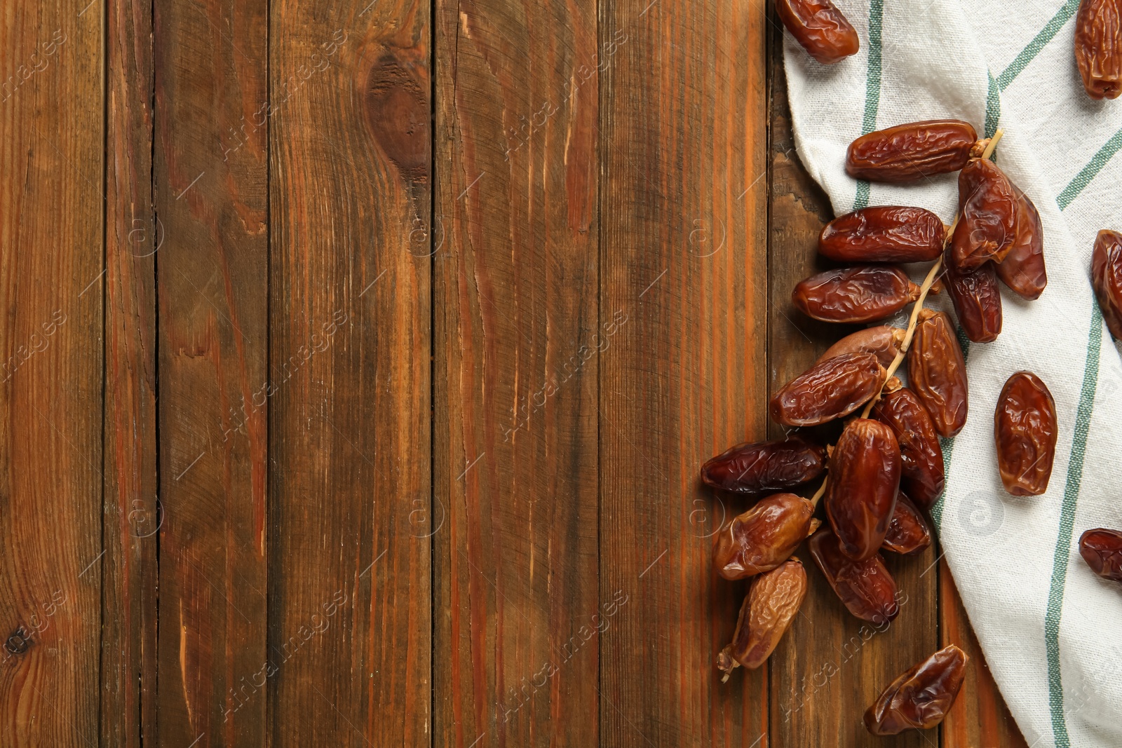 Photo of Branch with sweet dried dates on wooden table, flat lay. Space for text