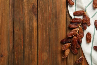 Branch with sweet dried dates on wooden table, flat lay. Space for text