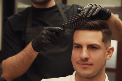 Photo of Professional hairdresser making stylish haircut in salon, closeup