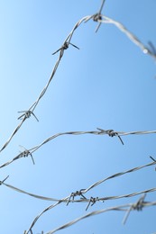 Metal barbed wire on light blue background