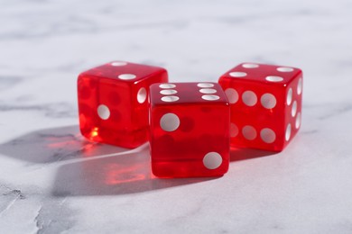 Photo of Three red game dices on white marble table, closeup