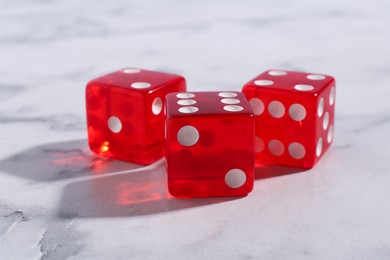 Three red game dices on white marble table, closeup