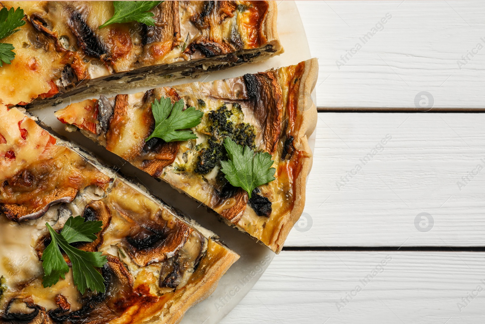 Photo of Delicious quiche with mushrooms and parsley on white wooden table, closeup. Space for text
