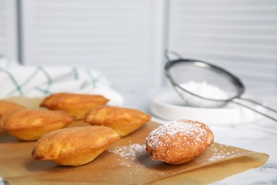 Photo of Delicious madeleine cakes on white table, closeup. Space for text