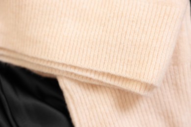 Photo of Soft beige sweater on black fabric, above view