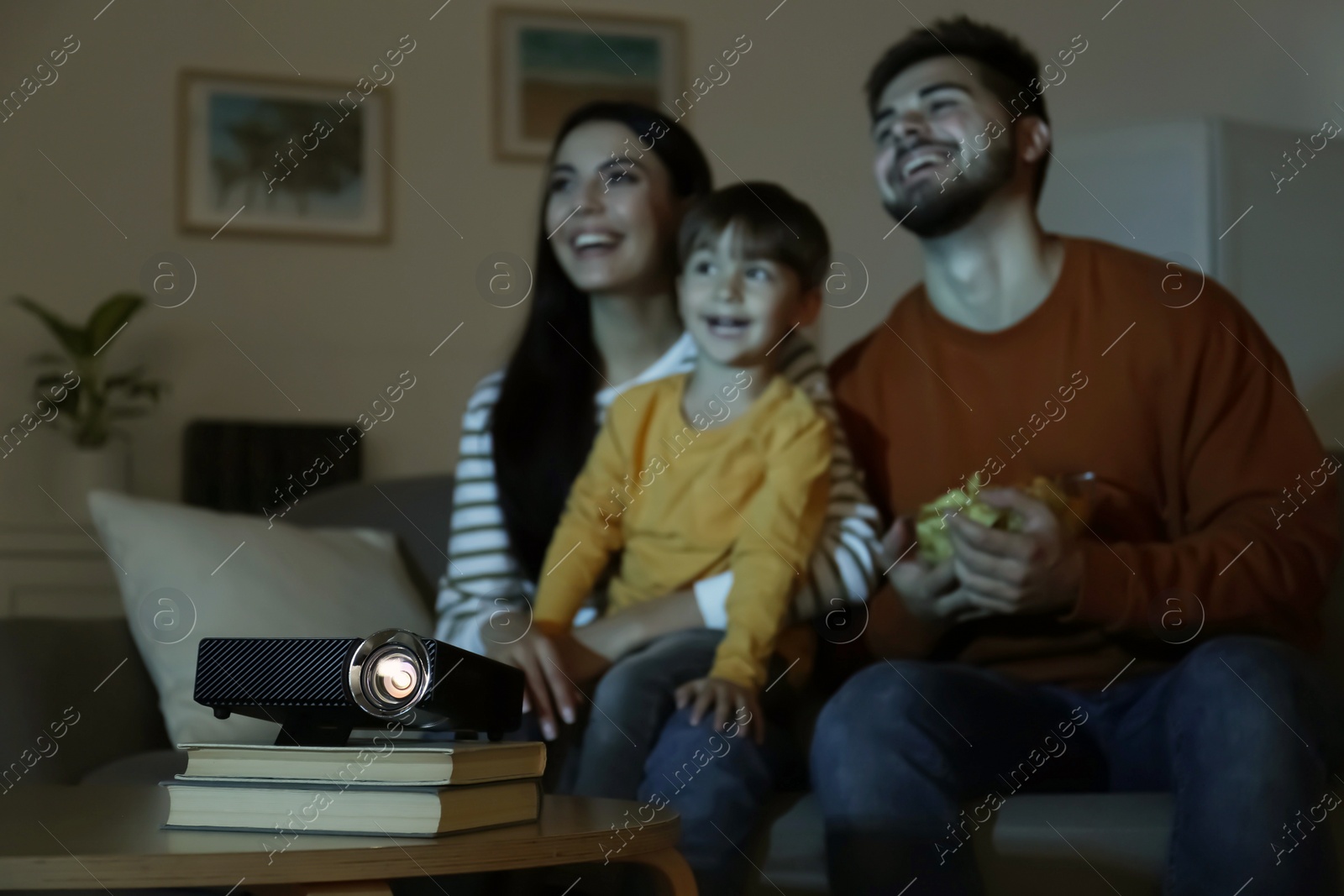 Photo of Family watching movie at home, focus on video projector