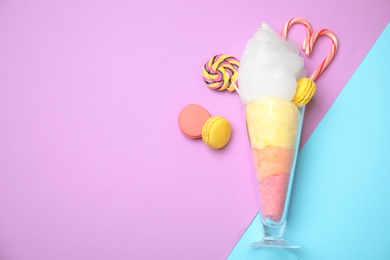 Photo of Composition with cotton candy in glass and space for text on color background, top view