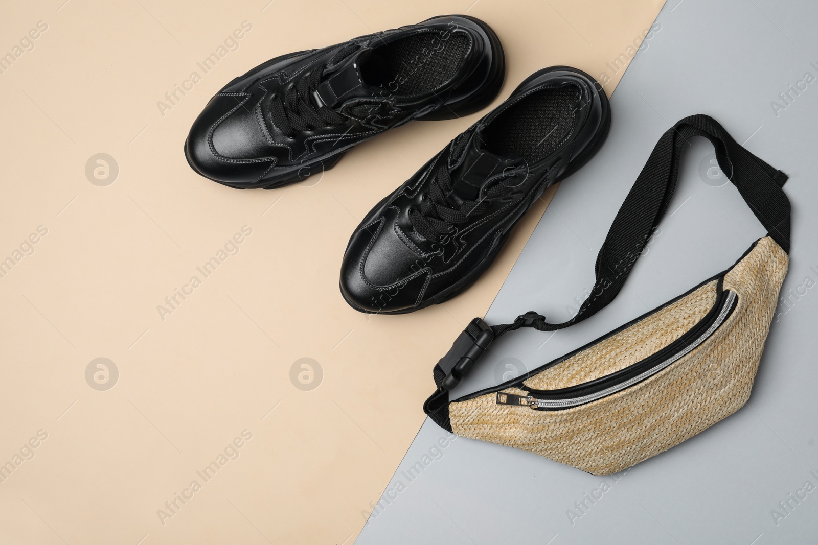 Photo of Stylish black sneakers and fanny pack on color background, flat lay. Space for text