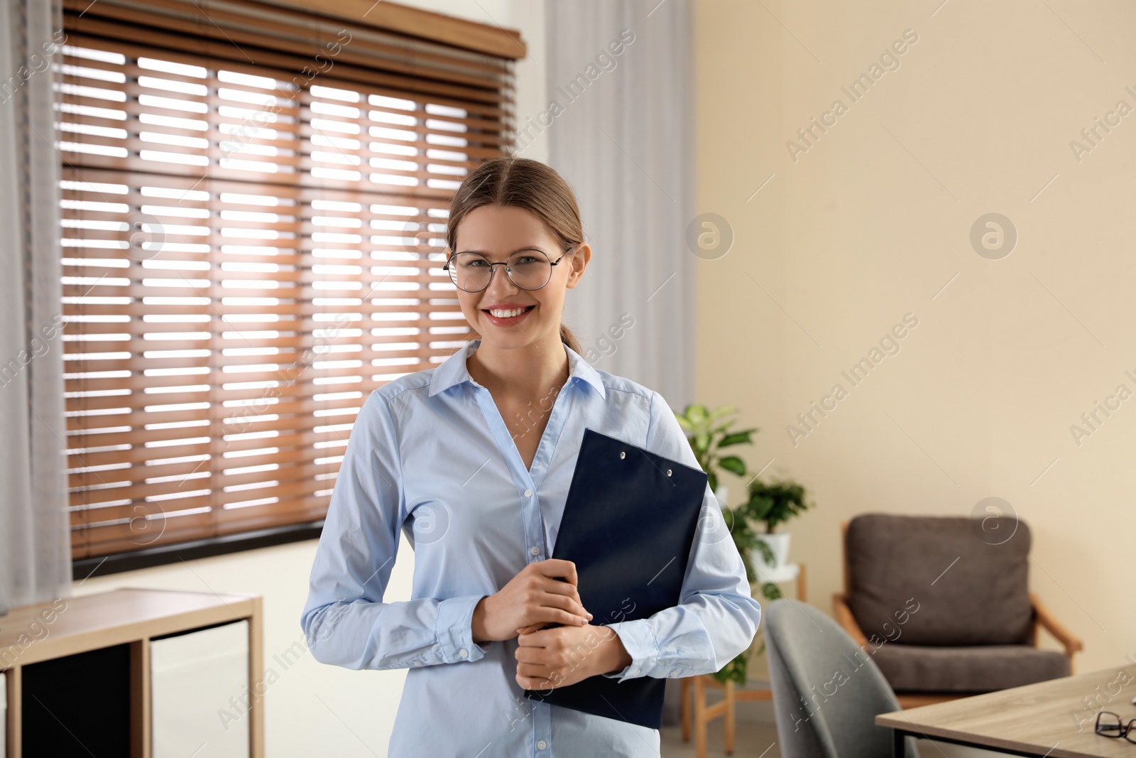 Photo of Professional psychotherapist with glasses and clipboard in office