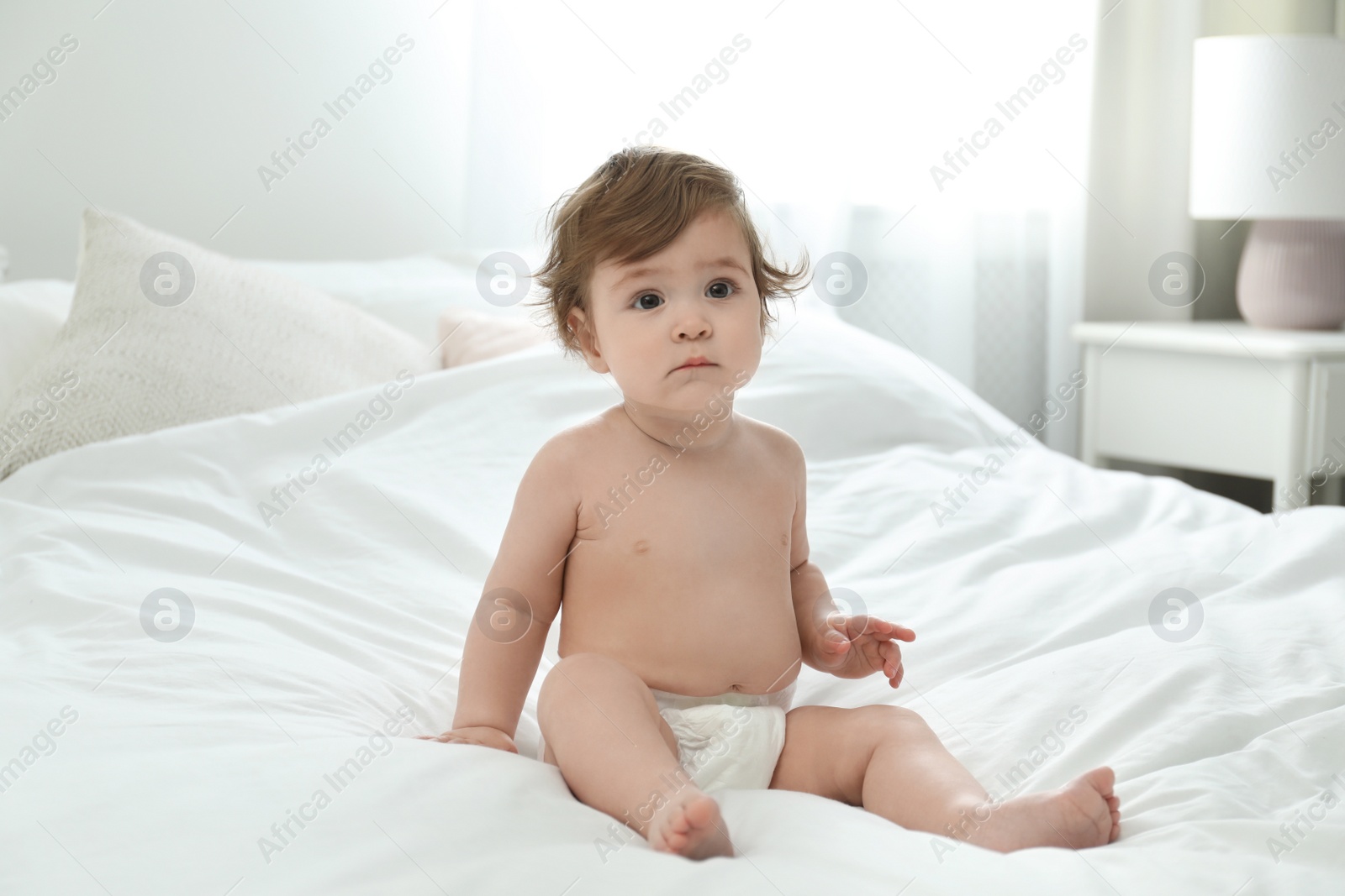 Photo of Cute little baby in diaper on bed