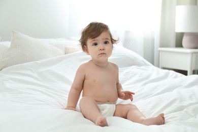 Cute little baby in diaper on bed