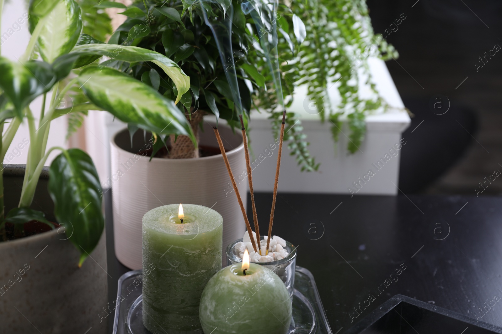 Photo of Candles and incense sticks on black table indoors. Zen and harmony