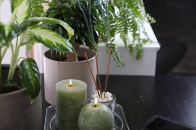 Photo of Candles and incense sticks on black table indoors. Zen and harmony