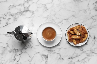 Photo of Tasty cantucci, cup of aromatic coffee and moka pot  on white marble table, flat lay. Traditional Italian almond biscuits