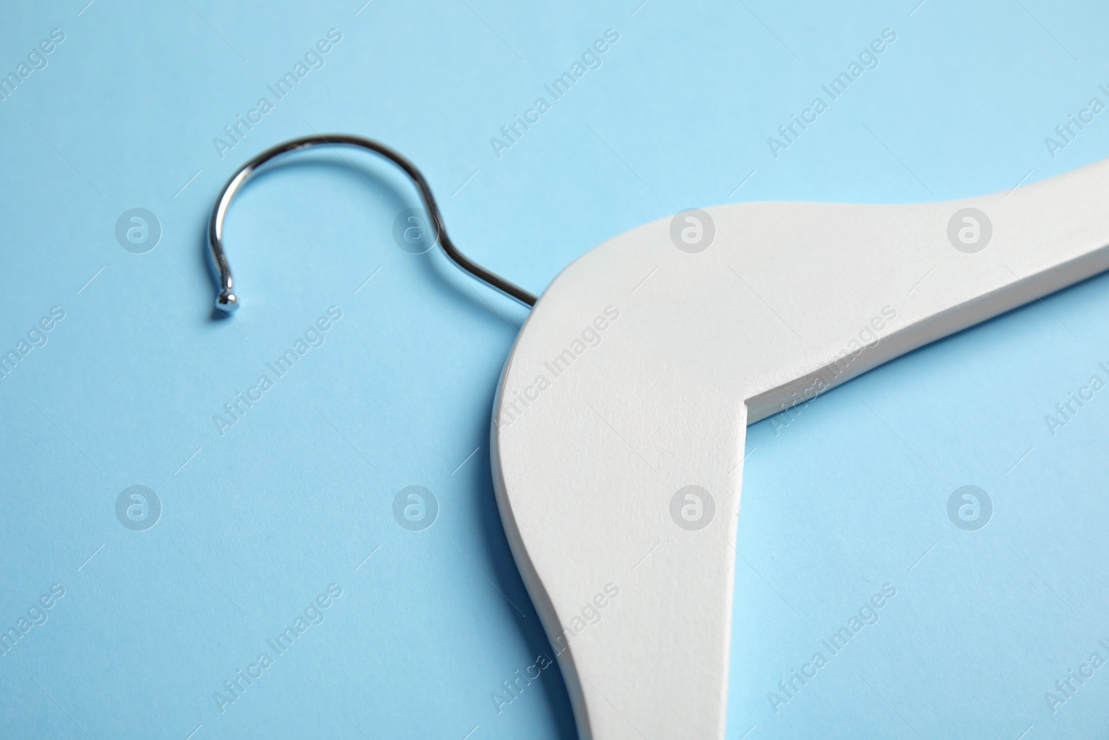 Photo of Empty wooden clothes hanger on color background