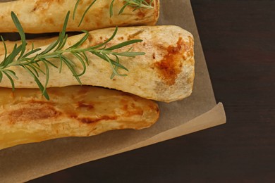 Photo of Tasty baked parsnips and rosemary on wooden table, top view