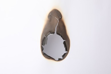 Photo of Burnt hole in paper on white background