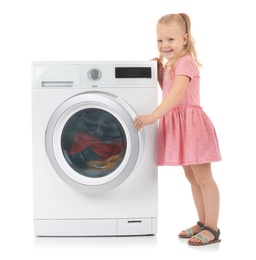 Cute little girl near washing machine with laundry on white background