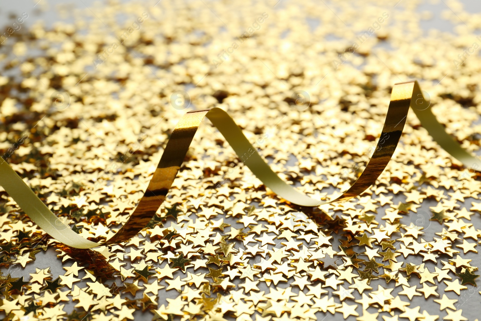 Photo of Confetti stars and streamer on grey background, closeup. Christmas celebration