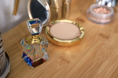 Photo of Luxury perfume, cosmetics and accessories on wooden dressing table, closeup