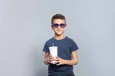 Photo of Boy with 3D glasses and beverage during cinema show on grey background