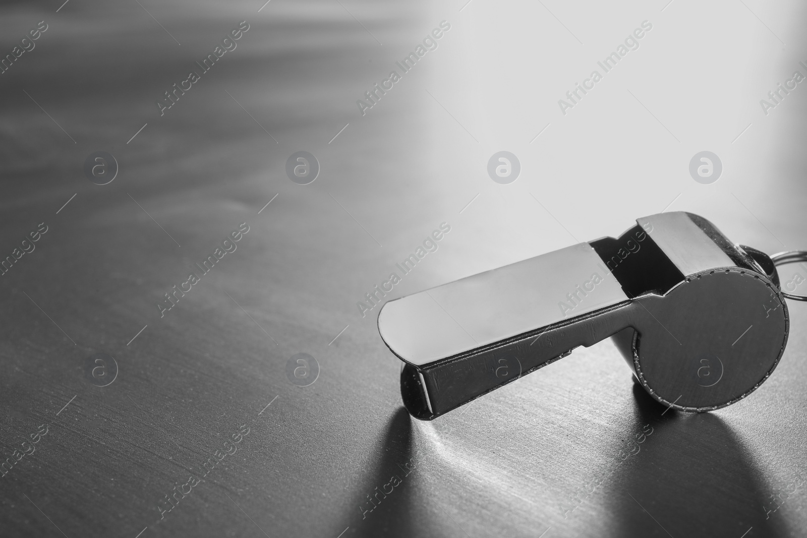 Photo of Referee equipment. Metal whistle on grey table, closeup and space for text