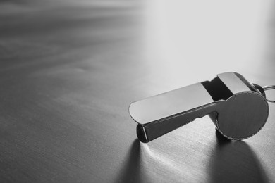 Photo of Referee equipment. Metal whistle on grey table, closeup and space for text