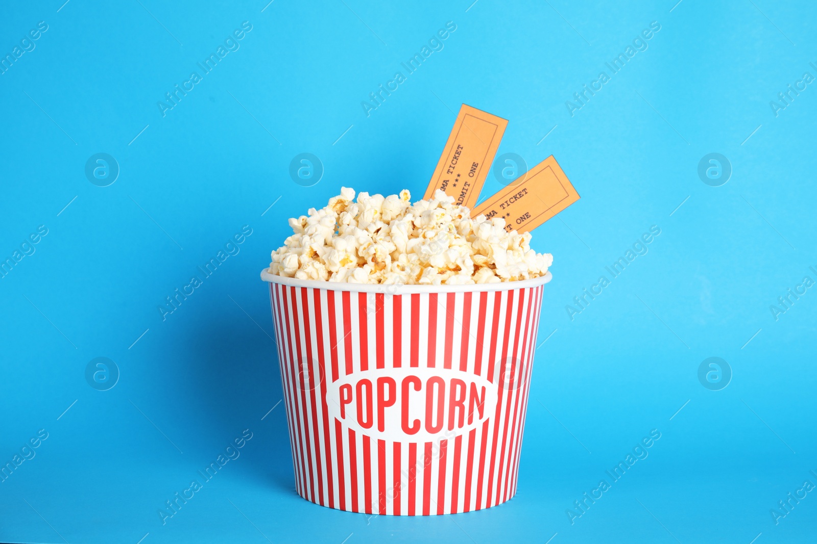 Photo of Bucket of fresh tasty popcorn and tickets on color background. Cinema snack