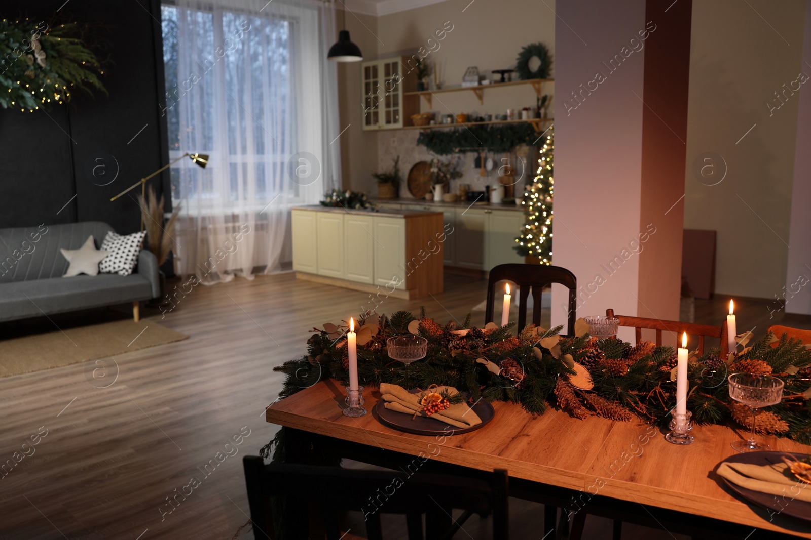 Photo of Dining table with burning candles and Christmas decor in stylish room. Interior design