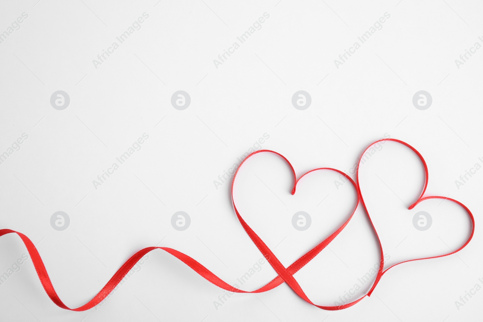 Photo of Hearts made of red ribbon on white background, top view. Valentine's day celebration