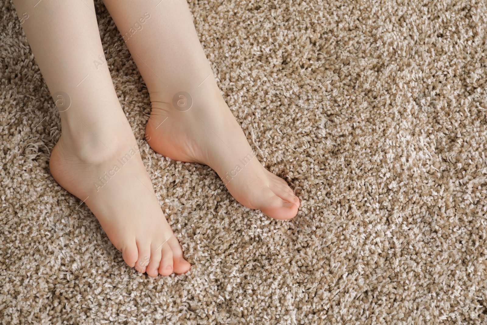 Photo of Woman on soft brown carpet at home, top view. Space for text