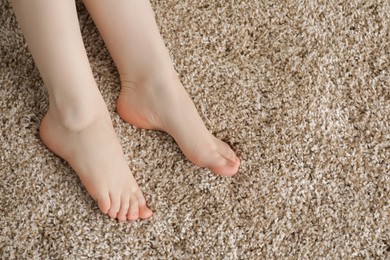 Photo of Woman on soft brown carpet at home, top view. Space for text