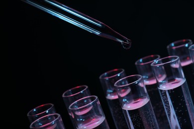 Photo of Dripping reagent into test tube on black background, closeup. Laboratory analysis