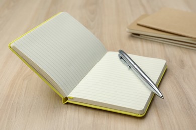 Photo of Open notebook and pen on wooden table. Personal planning