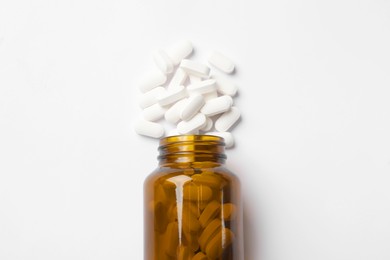 Photo of Vitamin pills and bottle on white background, top view