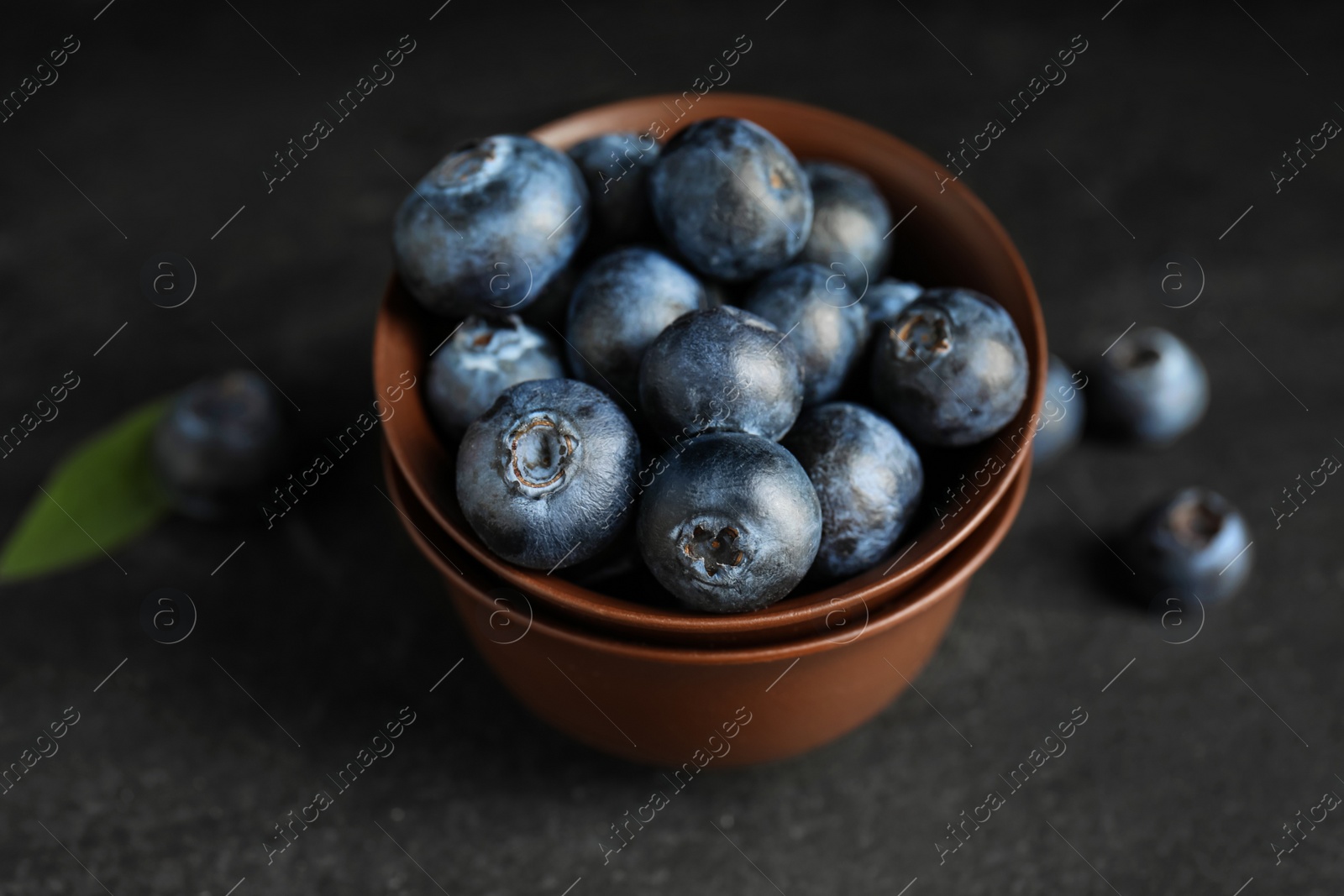 Photo of Fresh ripe blueberries in bowl on dark table, closeup