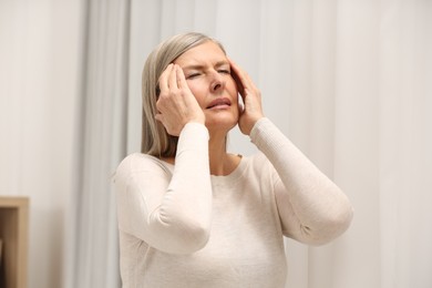 Menopause. Woman suffering from headache at home