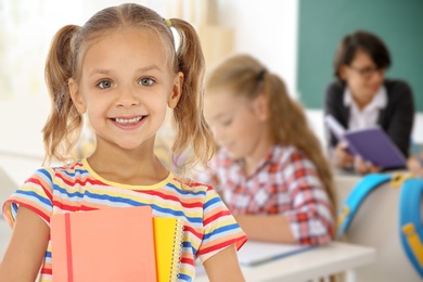 Image of Happy girl with notebooks in school classroom