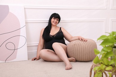 Photo of Beautiful overweight woman in black underwear posing at home. Plus-size model