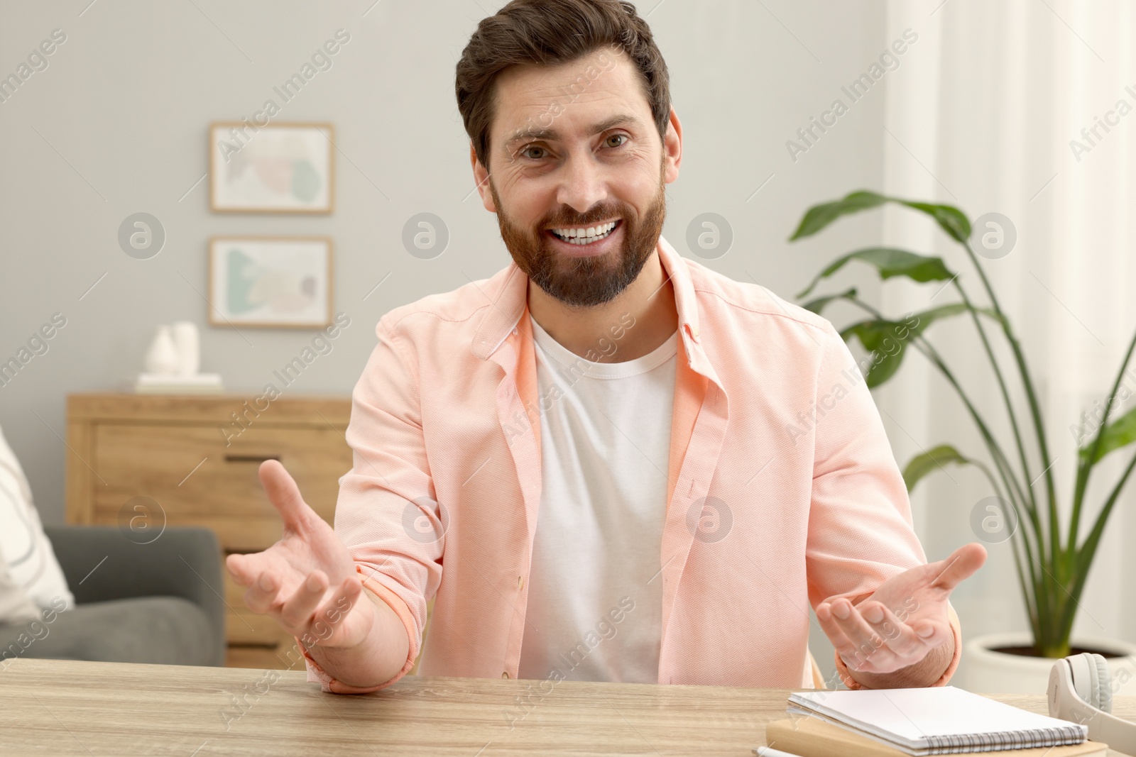 Photo of Man talking to someone at wooden table indoors