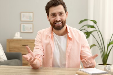 Man talking to someone at wooden table indoors