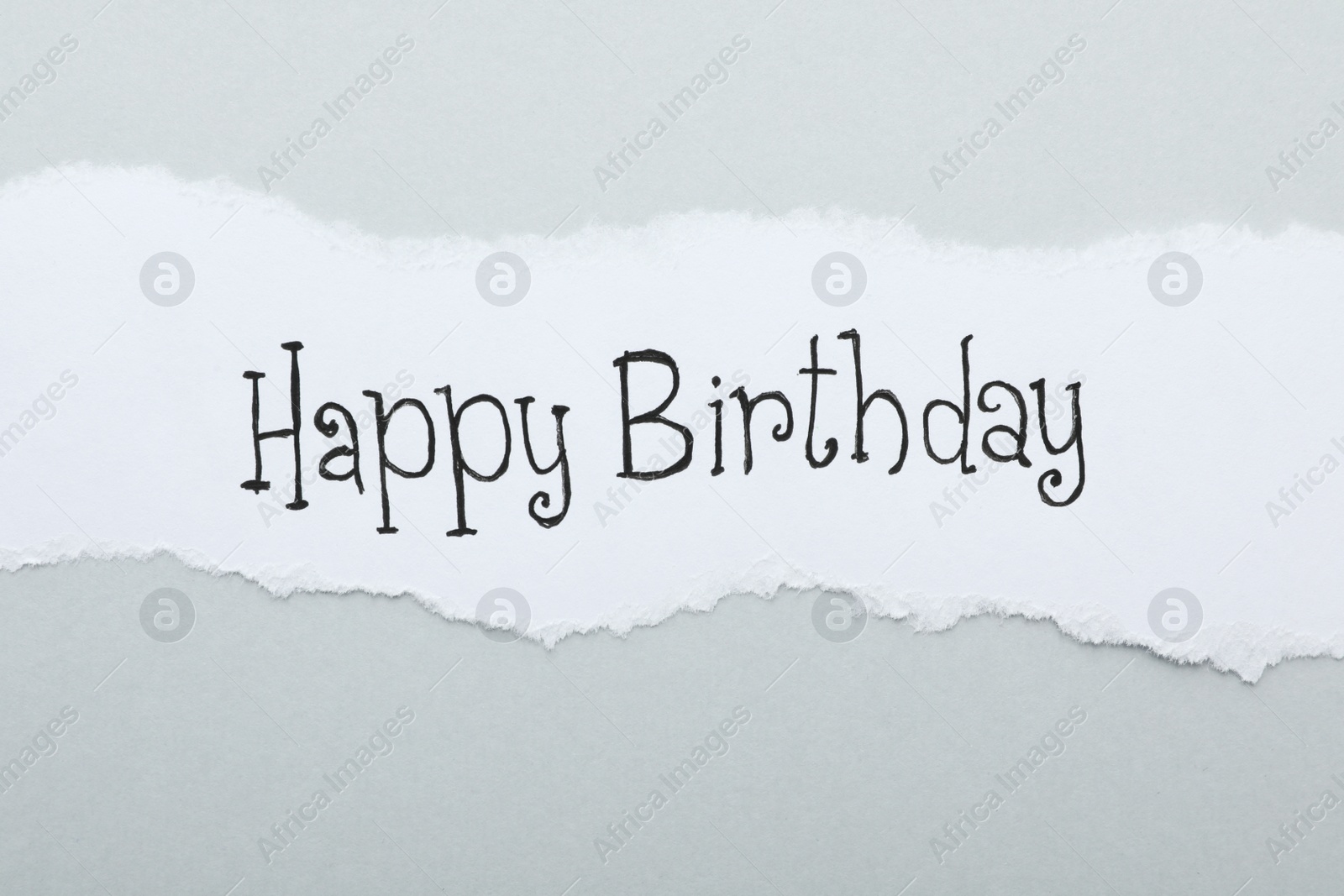 Photo of Sheet of paper with words HAPPY BIRTHDAY on light grey background, top view