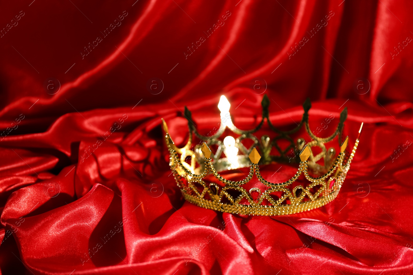 Photo of Beautiful golden crown on red fabric. Fantasy item