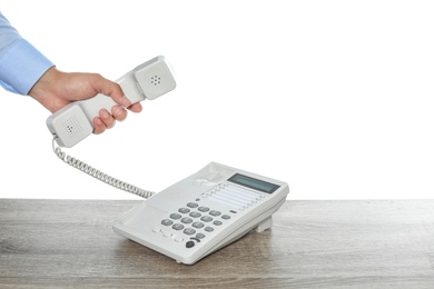 Photo of Man using telephone at table against white background, closeup