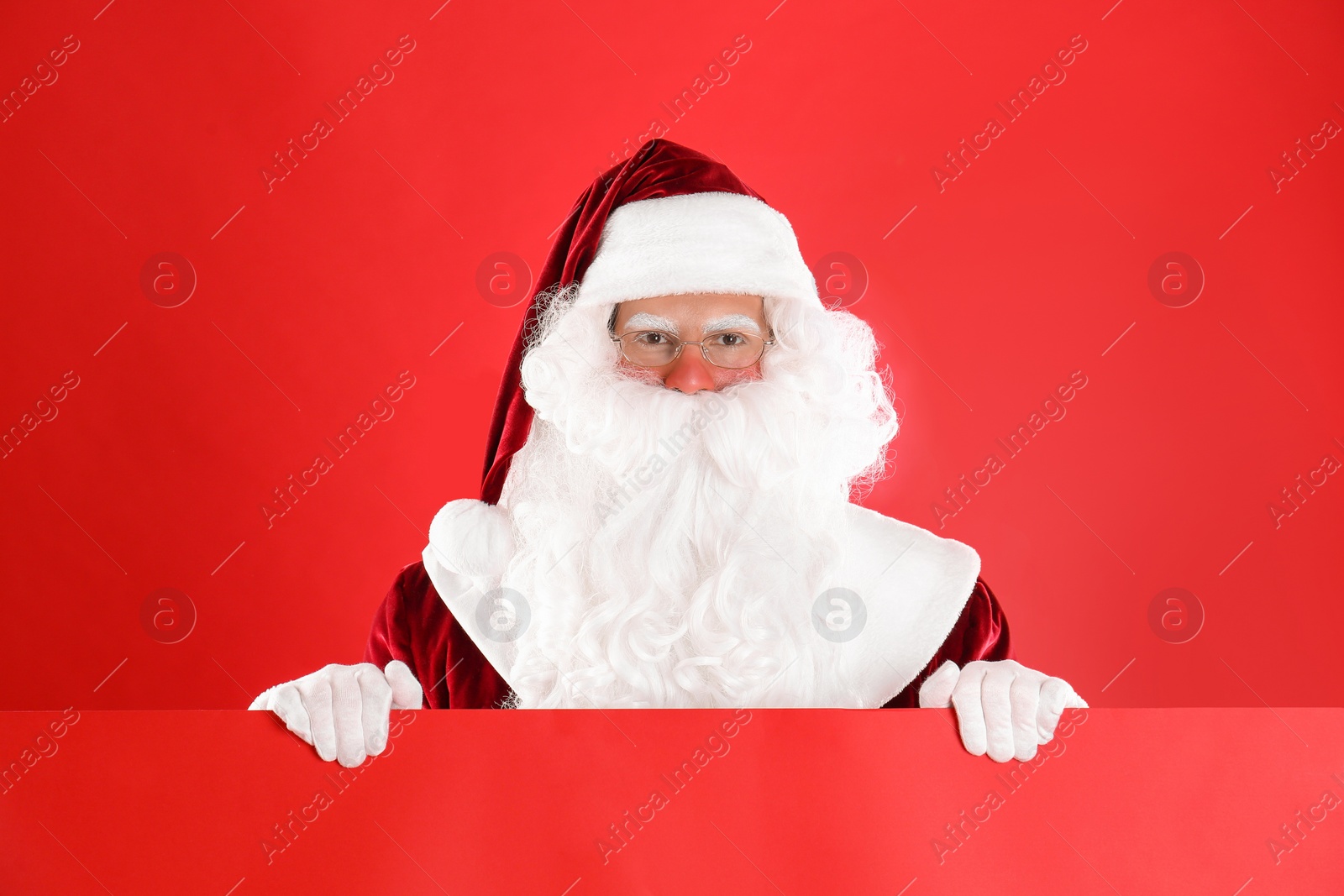Photo of Santa Claus holding empty banner on red background