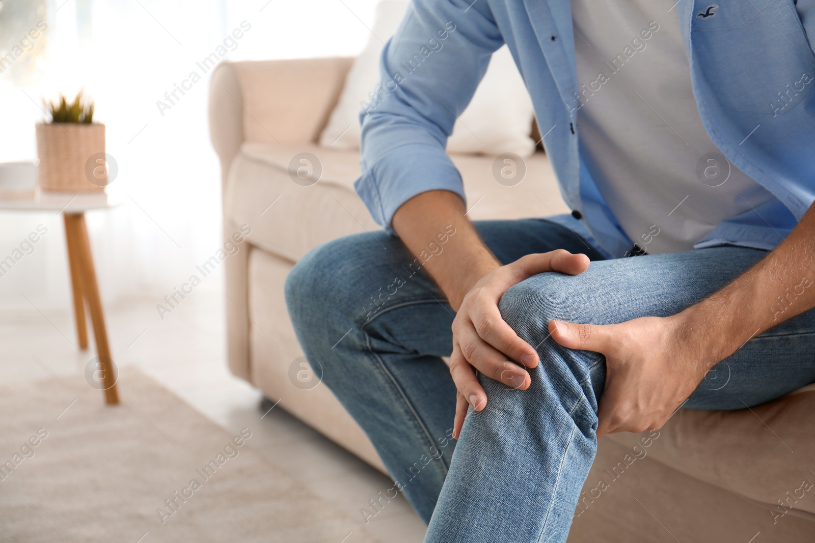 Photo of Man suffering from knee pain at home, closeup. Health problems