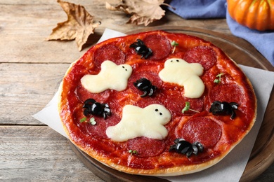 Photo of Cute Halloween pizza with ghosts and spiders served on wooden table