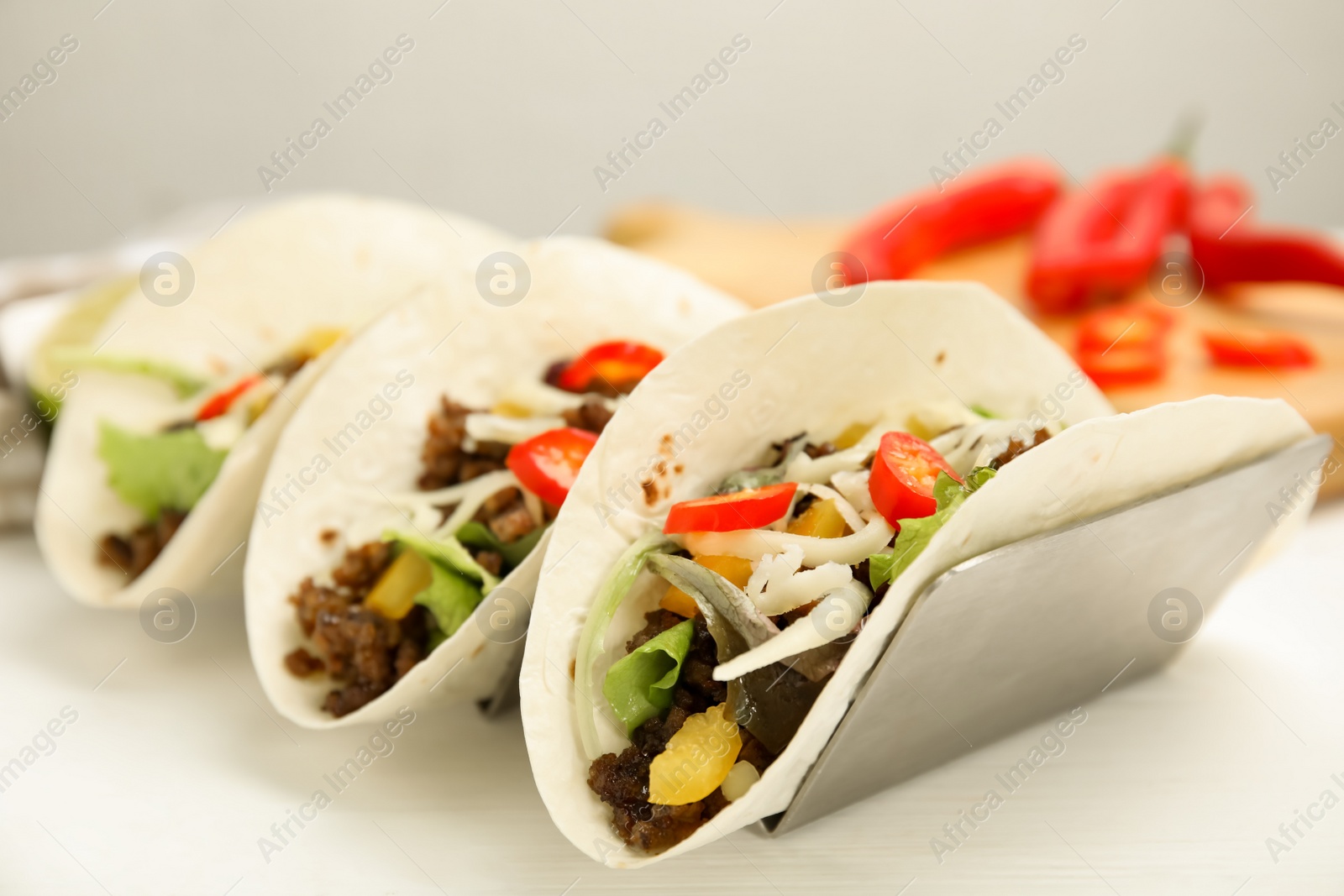 Photo of Delicious tacos with fried meat, vegetables and cheese on white wooden table, closeup